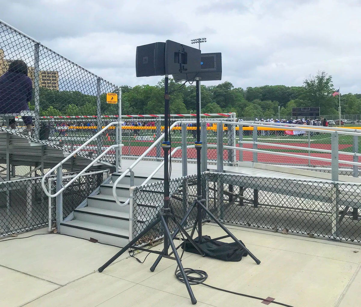 Outdoor PA speaker system on stands at New Jersey school athletic event with running track